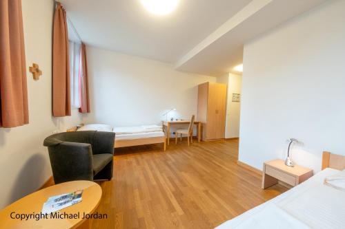 a living room with a bed and a desk at Gastflügel der Abtei Maria Laach in Glees