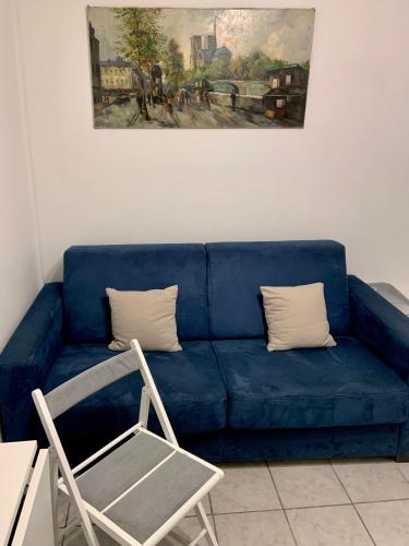- un canapé bleu avec deux oreillers et une chaise dans l'établissement Cozy little duplex near Montmartre, à Paris