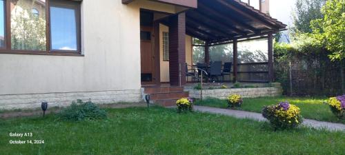 a house with a porch with flowers in the yard at Villaweb Ground Floor ap in a house, 5min drive to center&airport, villa can accomodate 12-18pers in Iaşi