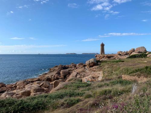 a lighthouse on a rocky shore with the ocean at Amour Amour Love Room in Penvénan
