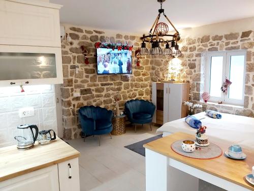 a room with a bed and a kitchen with blue chairs at Stone sea apartment in Risan