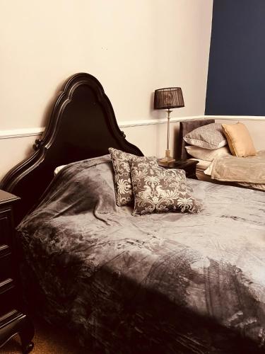a bed with a black headboard and pillows on it at Spacious 5 Bedroom Home in Central Kidderminster with Private Parking and Electric Vehicle Facilities, Easy Access to Birmingham and Nearby Towns in Kidderminster