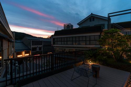 a balcony with two chairs and a building at Taikyourou in Miyazu