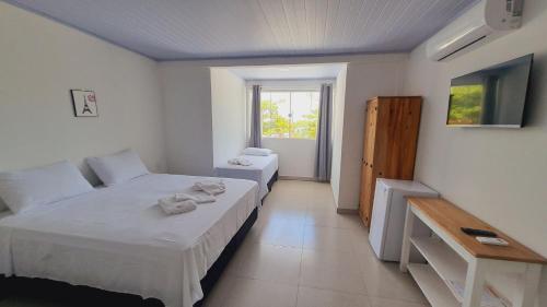 a room with two beds and a television in it at iG Pousada - Frente Mar in Florianópolis