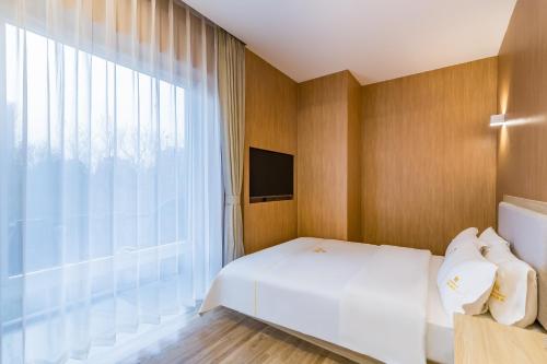 a bedroom with a white bed and a large window at Dequan Hotel Guangqumen Outer Branch in Beijing