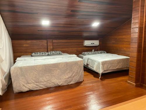 two beds in a room with wooden walls at Casa do Lago Pinhal in Rio dos Cedros