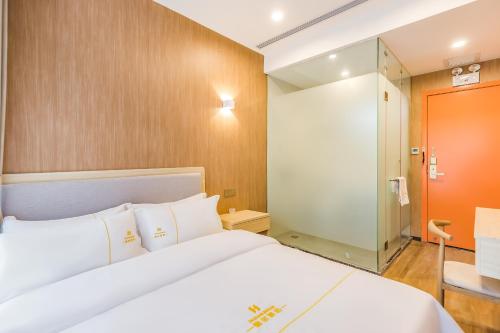 a bedroom with a white bed and a glass door at Dequan Hotel Guangqumen Outer Branch in Beijing