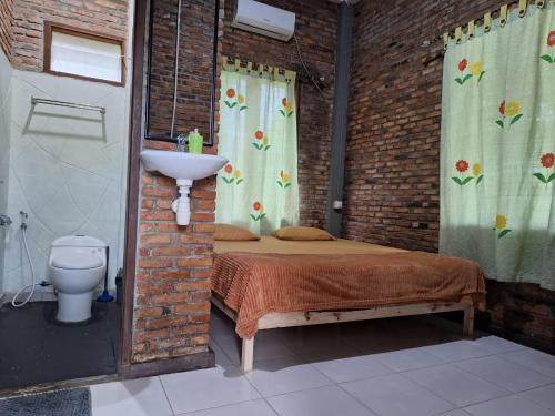 a bedroom with a bed and a sink in a brick wall at Bua Guest House in Medan