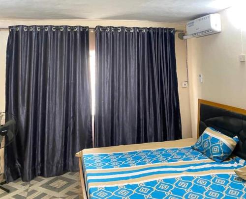 a bedroom with a bed and a window with curtains at Cosy 2 Bedroom Furnished Apartment in Ibadan