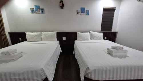 two beds in a room with white sheets and towels at Valentina Resort & Spa Phu Quoc in Phu Quoc