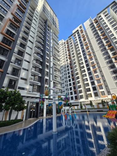two tall apartment buildings with a swimming pool in front at K Avenue Sunset View Condomonium - Kota Kinabalu Airport in Kota Kinabalu