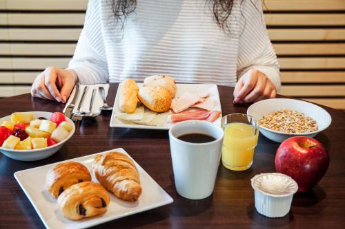 a woman sitting at a table with plates of breakfast foods at Ibis Budget Madrid Alcorcón Móstoles in Alcorcón