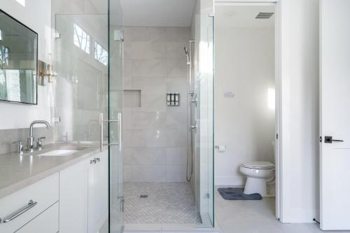 a white bathroom with a shower and a toilet at Elegant 3-Story House with Private Backyard in WA in Kirkland