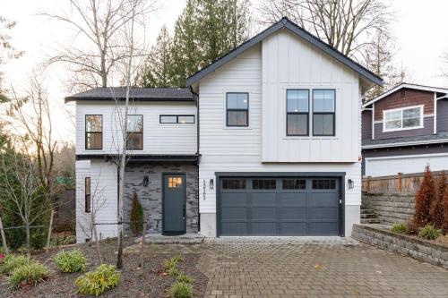 a white house with a blue garage door at Elegant 3-Story House with Private Backyard in WA in Kirkland