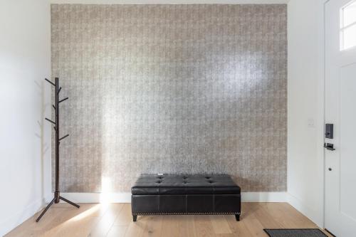 a room with a black ottoman in front of a wall at Elegant 3-Story House with Private Backyard in WA in Kirkland