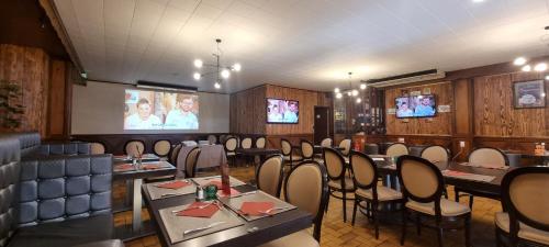 une salle à manger avec des tables, des chaises et des télévisions dans l'établissement Auberge du Bois de l'étang - Motel les Tilleuls, à Peyrat-le-Château