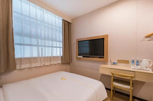 a room with a bed and a desk and a television at Dequan Hotel Guangqumen Outer Branch in Beijing