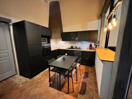 une cuisine avec des armoires noires et une table. dans l'établissement La Baudiniere - Maison avec jardin, à Artannes-sur-Indre