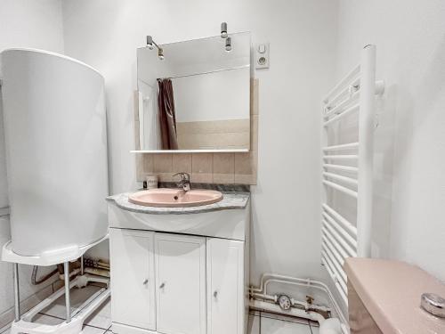 une salle de bain blanche avec un lavabo et un miroir dans l'établissement Duplex Nancy centre - Cour intérieure & Smart TV, à Nancy