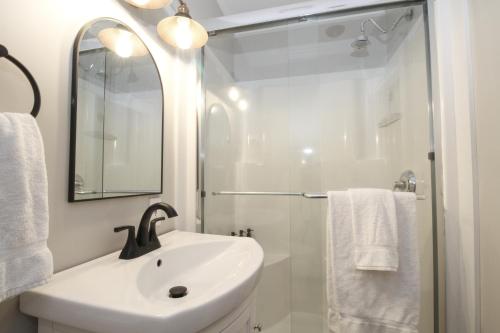 a white bathroom with a sink and a shower at The Aurora Inn & Cottages in Bartlett