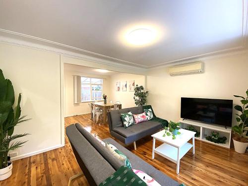 a living room with a couch and a tv at Creekside House in Pennant Hills