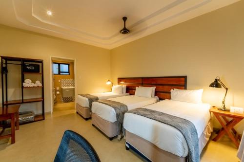 a bedroom with three beds and a table and a chair at The Shrub Lodge in Victoria Falls