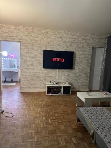 un salon avec une télévision sur un mur en briques dans l'établissement Cosy nest, à Aubergenville