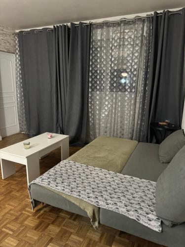 - une chambre avec un lit, une table et des rideaux dans l'établissement Cosy nest, à Aubergenville