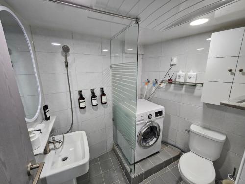 a bathroom with a toilet and a washing machine at Busan Subway 6min #2 Rooms #2 Queen Beds #Hotel Bedding #OTT #Table#1st Floor in Busan