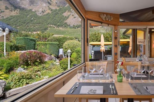 a dining room with a table and a view of a garden at Relais de la Sarvaz in Saillon