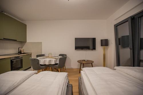 a room with two beds and a table and a kitchen at Central Suite in Trebinje