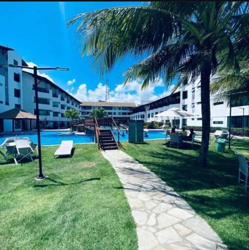 a resort with a swimming pool and a palm tree at MAUÍ BEACH Tamandaré Flat Terreo in Tamandaré
