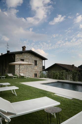 a backyard with a pool and chairs and a house at Cascina Belvedì in Clanezzo