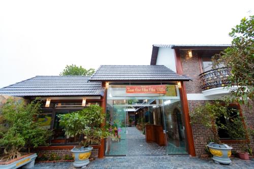 a brick building with a storefront with potted plants at Tam Coc Chu Chu Villa in Ninh Binh