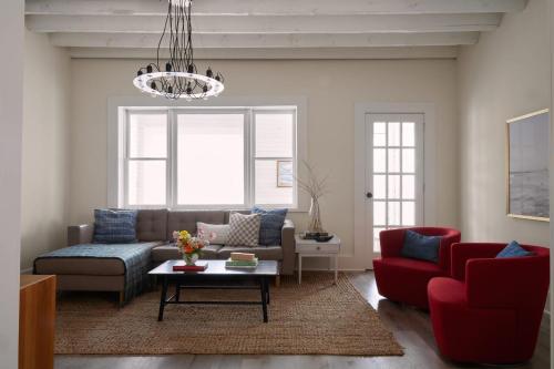 a living room with a couch and red chairs at Harbour Main playful century home w private patio in Picton