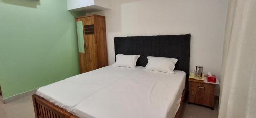 a bedroom with a white bed with a black headboard at The Pearl Munro in Munroe Island