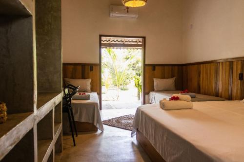 a bedroom with two beds and a door to a patio at Casa agradável no sossego de BG: até 18 pessoas in Barra Grande