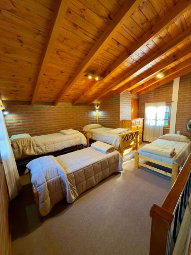 a room with four beds and a wooden ceiling at Complejo Entre Olmos in Santa Rosa de Calamuchita