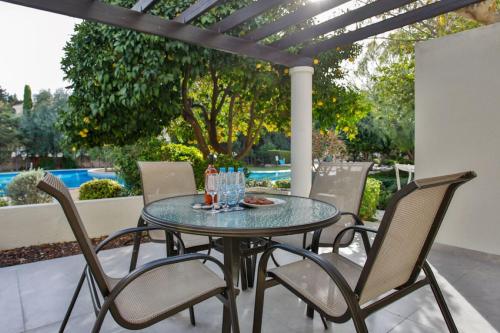 a glass table and chairs on a patio at Stunning & Cosy, Direct Pool Access, 2BR, with Private Patio! Serenity Townhouse in Paphos