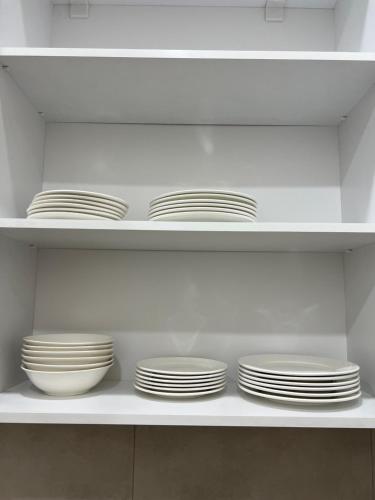 a shelf with white plates and bowls on it at Velvet Vouge Hostel in Yerevan