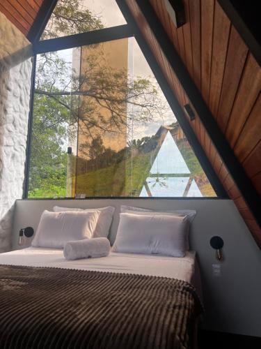 a bed in a room with a large window at Chalé Cabana Morro dos Ventos in Chapada dos Guimarães