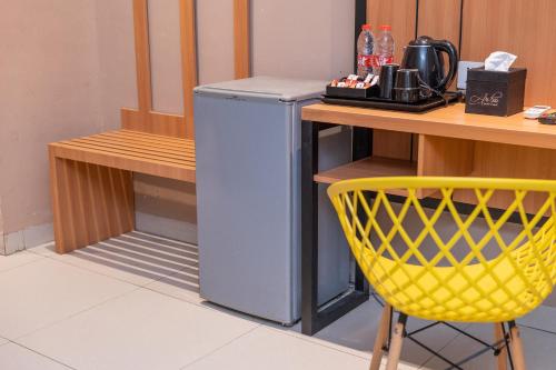 a yellow chair next to a table and a refrigerator at A'rabia Style Wahid Hasyim in Medan