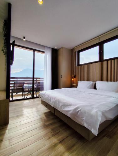 a bedroom with a large white bed and a balcony at Meteora Gold and Glass Suites in Kalabaka