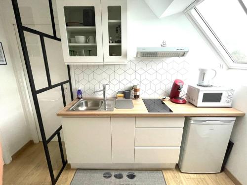 a small kitchen with a sink and a microwave at Hébergement Golfe du Morbihan - Ty Baden in Baden
