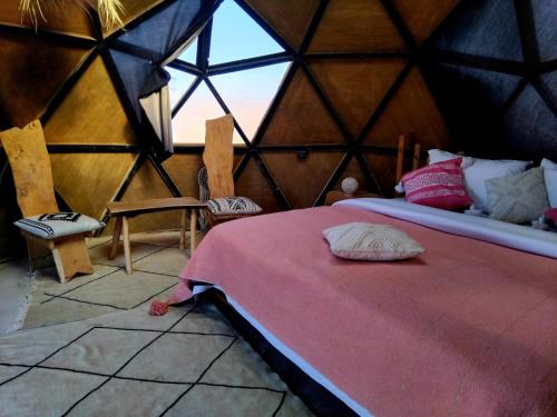 Habitación con cama en una yurta con ventana en Chic Boheme Camp, en Merzouga