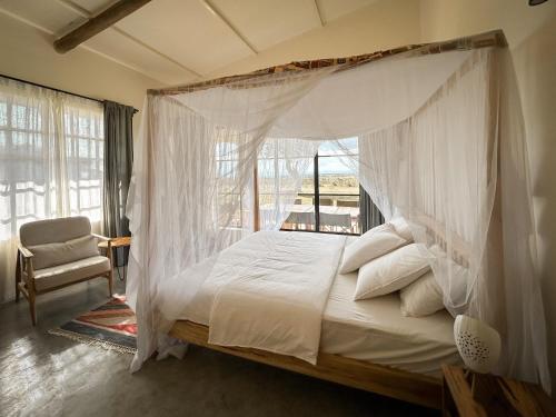 a bedroom with a canopy bed and a chair at Kobe Mara in Talek