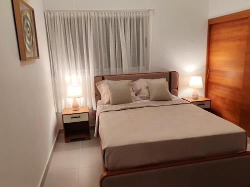 a bedroom with a bed and two lamps on tables at Style and Confort Apart Villa Palmera in Santo Domingo