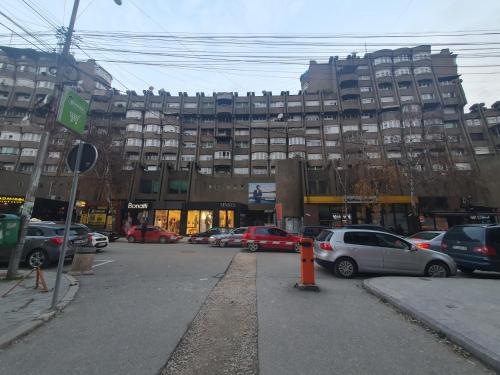 a parking lot with cars parked in front of a large building at Turquoise Apartment in Novi Pazar