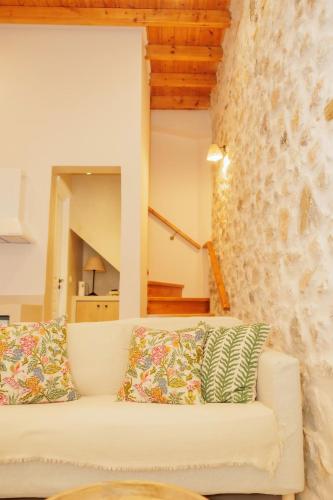 a living room with a white couch and a stone wall at Caeli's Home in Gythio