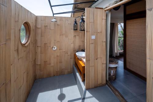 une salle de bain avec des murs en bois, un lavabo et un miroir dans l'établissement Menjangan Dynasty Resort, à Banyuwedang